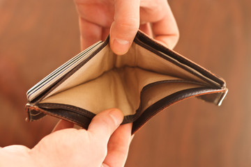 Hands opening an empty wallet against blurred background