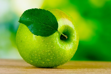 Healthy ripe dropped apple on wooden table outside