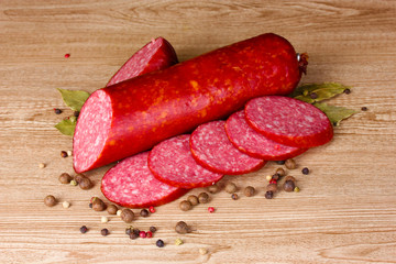 Tasty sausage and spices on wooden background