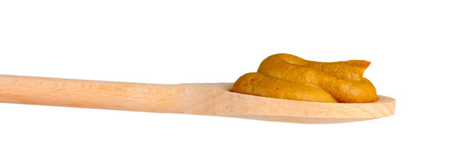 Mustard in a wooden spoon isolated on white