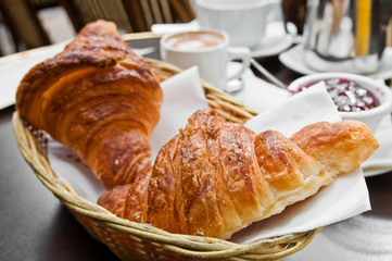 Breakfast with coffee and croissants in a basket on table