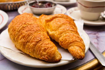 Breakfast with coffee and croissants in a basket on table