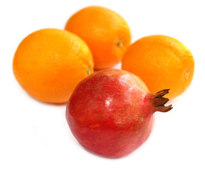 Ripe pomegranate with oranges in selective focus