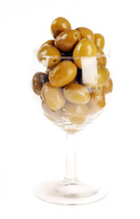 Green olives in wine glass on white background.