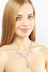 Portrait of a beautiful girl with necklace on gray