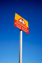 Danger Strong Currents Keep Clear warning sign against blue sky