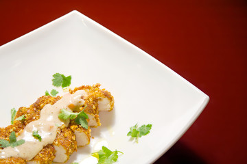 Pan fried pine nut chicken breast on plate against red