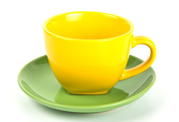 Yellow tea cup on green saucer isolated on white