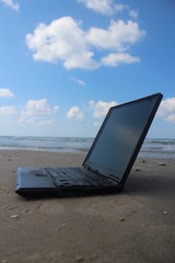 Laptop at the beach, near the sea, with sky background