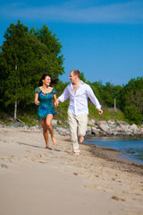 Enamored man and girl running along coast of sea