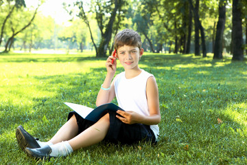 Naklejka na ściany i meble Portrait of a boy with a book in the park