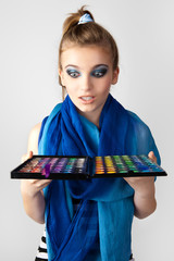 A girl admires make-up collection for creative visage.