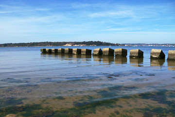 Concrete beach groyne projecting into blue sea against sky