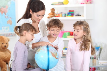 a woman and three little girls watching a globe