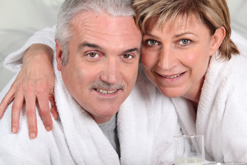 mature couple in sponge bathrobe embracing