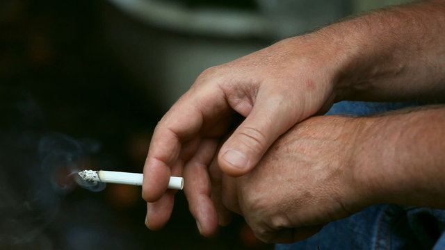 Man holding a smoking cigarette.
