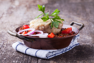 Gulasch mit Knödel auf einem Holzbrett