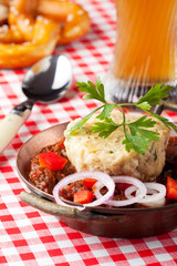Gulasch mit Knödel auf einem Holzbrett