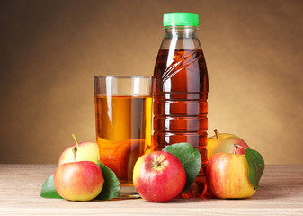 Apple juice and apples on wooden table on brown background