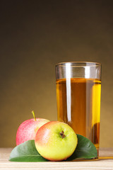 Apple juice and apples on wooden table on brown background