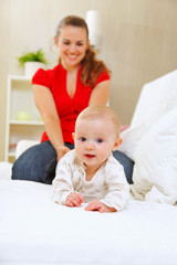 Smiling mother and adorable baby playing on sofa