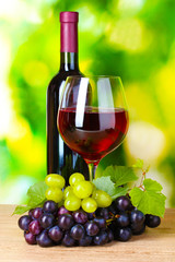 Obraz na płótnie Canvas Ripe grapes and glass of wine on green background