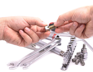 Hand with a nut and bolt on the background of wrenches