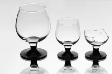 Two wineglasses with a broken one on the mirror