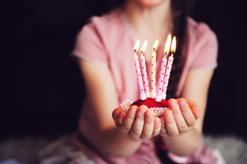 Child girl holding a cupcake with five candles