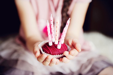 Child girl holding a cupcake with five candles