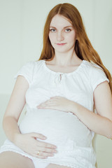 Beautiful young pregnant woman sitting on chair