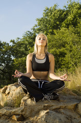 Woman meditating yoga on rock portrait