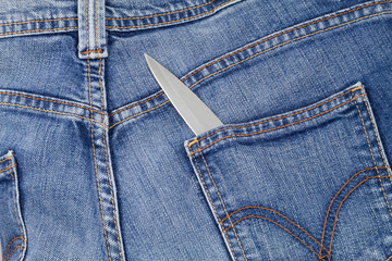 Knife blade showing out from a jeans back pocket