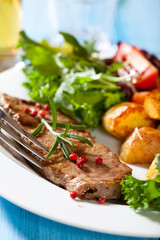 Grilled steak with baked potatoes and fresh vegetables