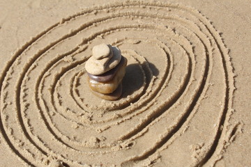 Fototapeta na wymiar Stones pyramid at the beach, circles in the sand