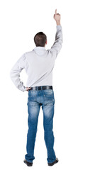 Fototapeta premium young man pointing at wall. rear view.