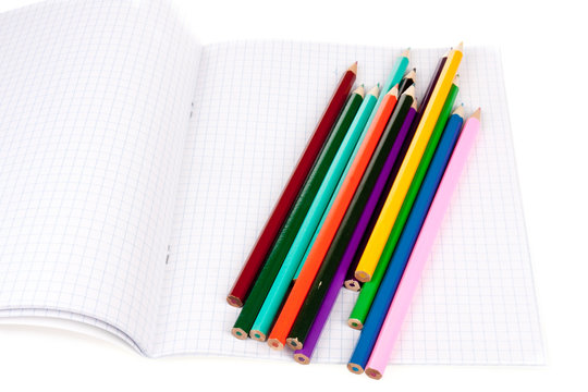 Exercise book with colored pencils isolated over white