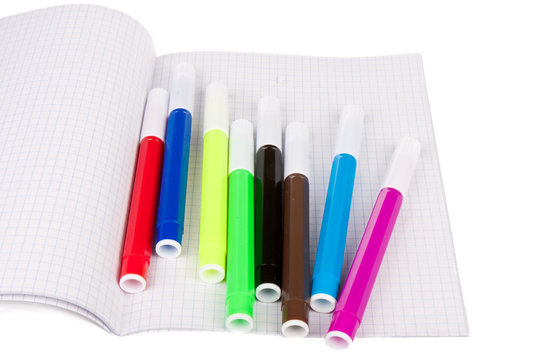 Exercise book with felt-pens isolated over white