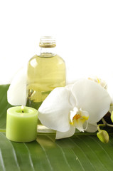 Fototapeta na wymiar white orchid, bottles with essential oil, on banana leaf