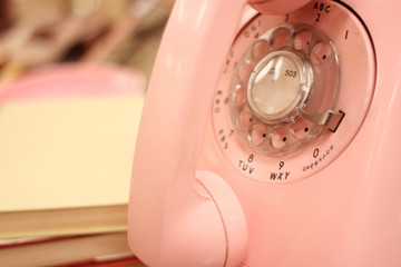 A pink rotary telephone on a desk.