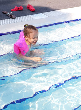 Joyful little girl swimming in the pool.