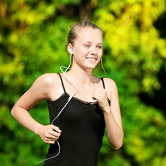 Fototapeta premium Young woman running in green park
