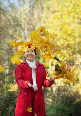 Happy mature woman throwing yellow  leaves