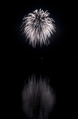 Clear white fireworks on black sky background with water reflect