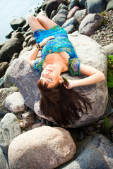 beautiful brunette girl lying on beach stones