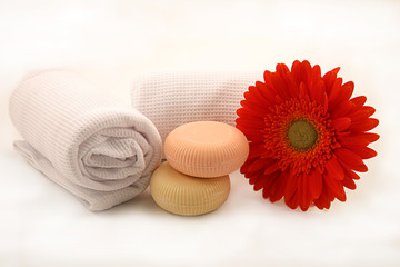 saponette con fiore e asciugamani su fondo bianco