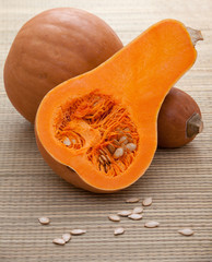 Ripe orange pumpkins with white seeds on straw woven surface