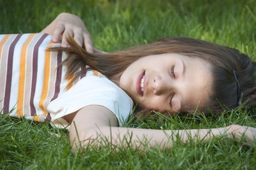 Pretty young teenage girl resting on the bed of grass.