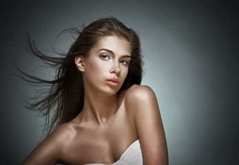 Beautiful woman with fluttering hair. On dark background.