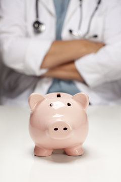 Doctor with Folded Arms Behind Piggy Bank